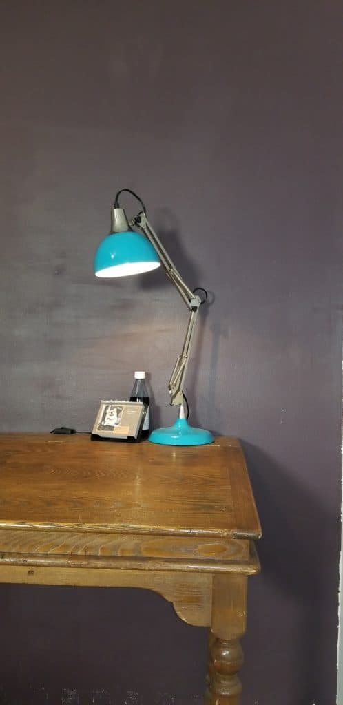 A Desk With A Lamp That'S Used As A Writing Space